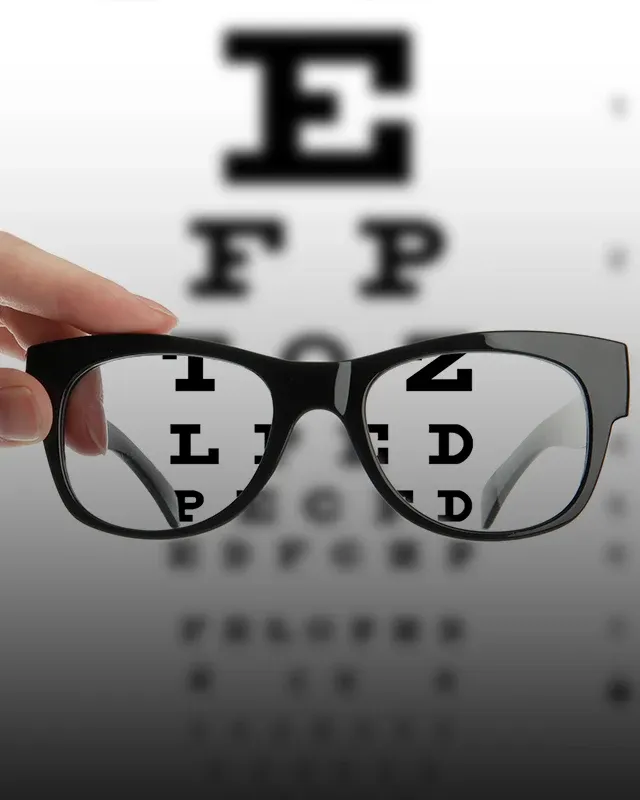Eyeglasses held in front of a Snellen chart, illustrating improved visual clarity.