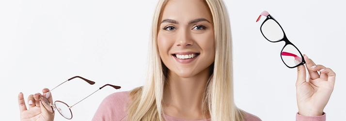 erson holding two different eyeglass frames, comparing styles and options for vision correction.